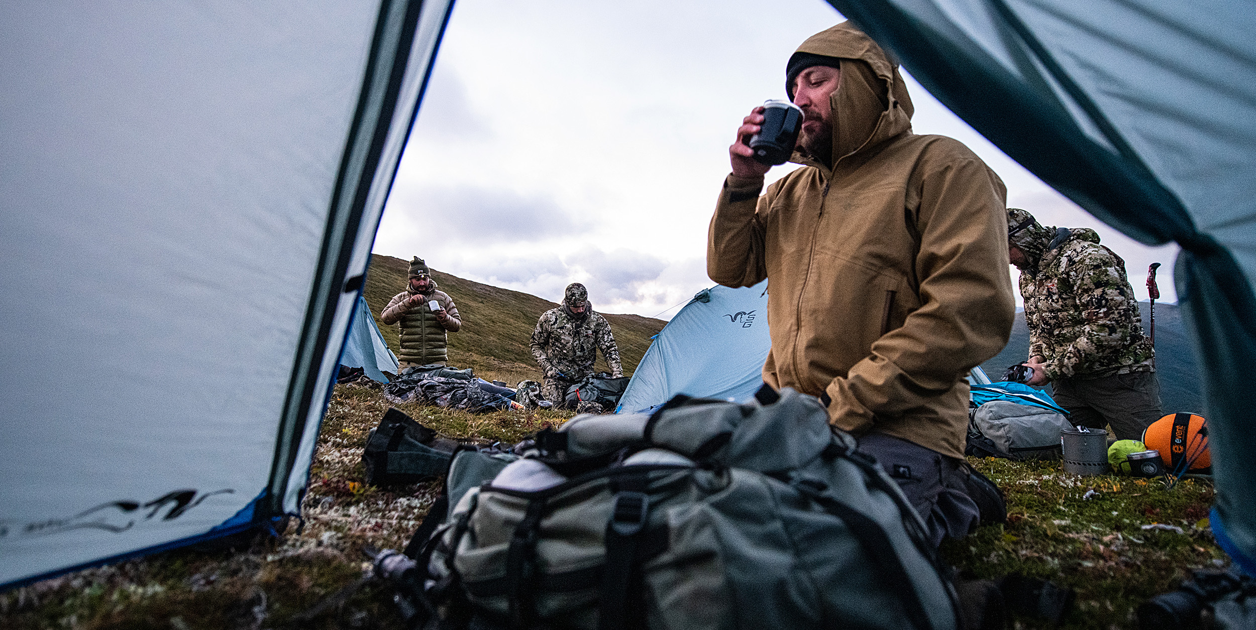 Hunter drinking coffee in tent on a mountain